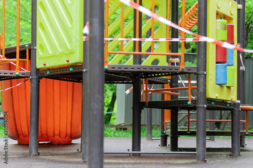 The play park of amusement and sports for young children is wrapped in red barrier tape. Outside. Prohibition of outdoor walks, prevention of the coronavirus influenza virus covid-19. stay home.