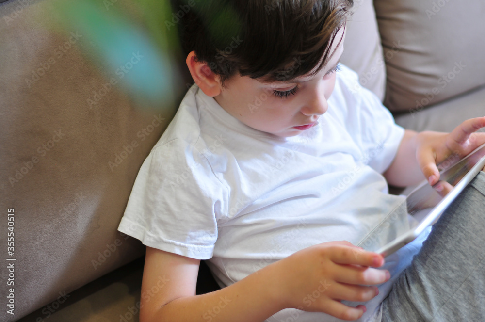 Closeup Of little kid boy Holding Digital Tablet top view. Childre with technologies studing or playing comuter games. Closeup Of little kid boy Holding Digital Tablet top view. Childre with technologies studing or playing comuter games.