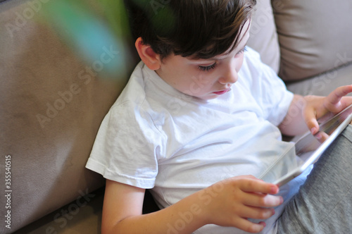 Closeup Of little kid boy Holding Digital Tablet top view. Childre with technologies studing or playing comuter games.