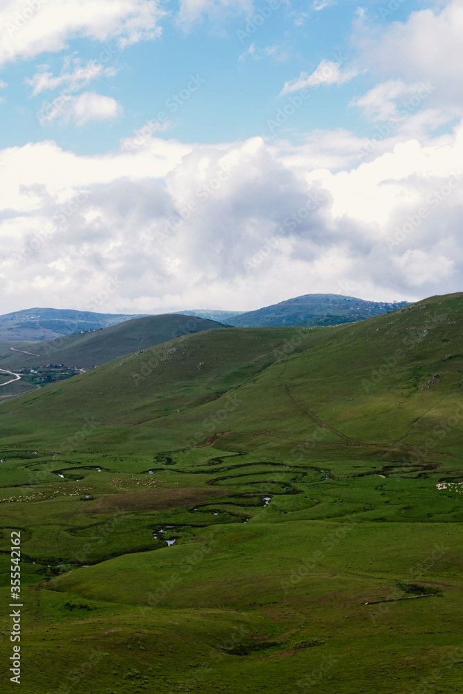 Meandering stream with mountains and clouds at The Persembe Plateau at Ordu, Turkey