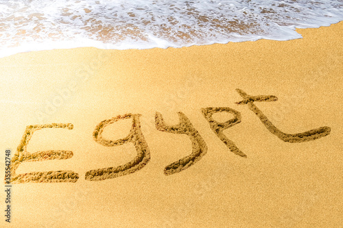 Egypt title on the sand beach of the Red sea. Brilliant sun ray falls on the letters. Hot season. Wave. © Anna Shnaider