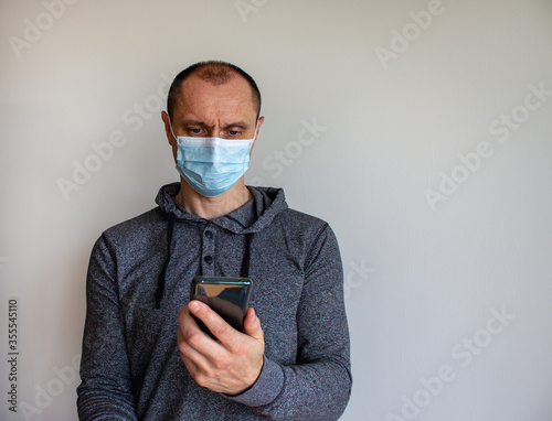 Young man with mobilphone wearing a protective medicine mask isolated on white background. photo