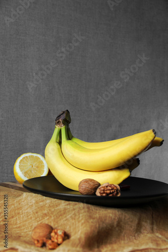 A bunch of bananas on a black plate. Yellow fruit. Contrast of colors. Bananas and lemons. Tropical fruits. Ripe bananas