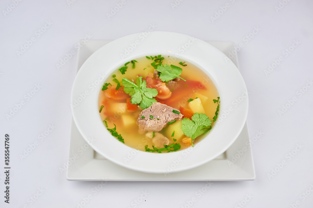 soup with meat, pepper, tomatoes, greens on a white background
