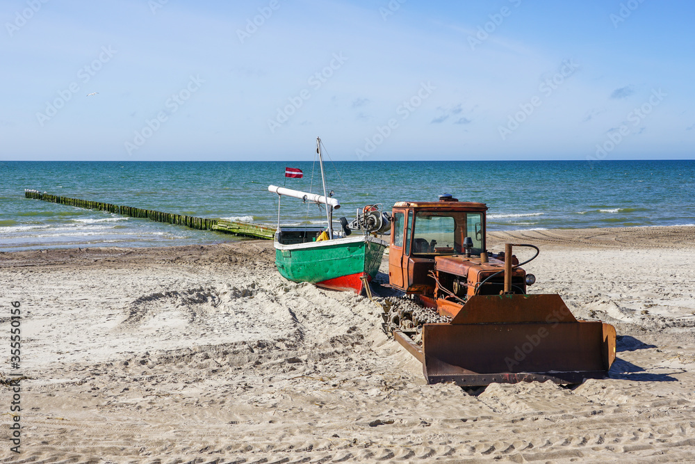 a heavy bulldozer pulls a fishing boat out of the sea