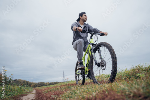 Fototapeta Naklejka Na Ścianę i Meble -  A man on a bicycle in the autumn on a field road