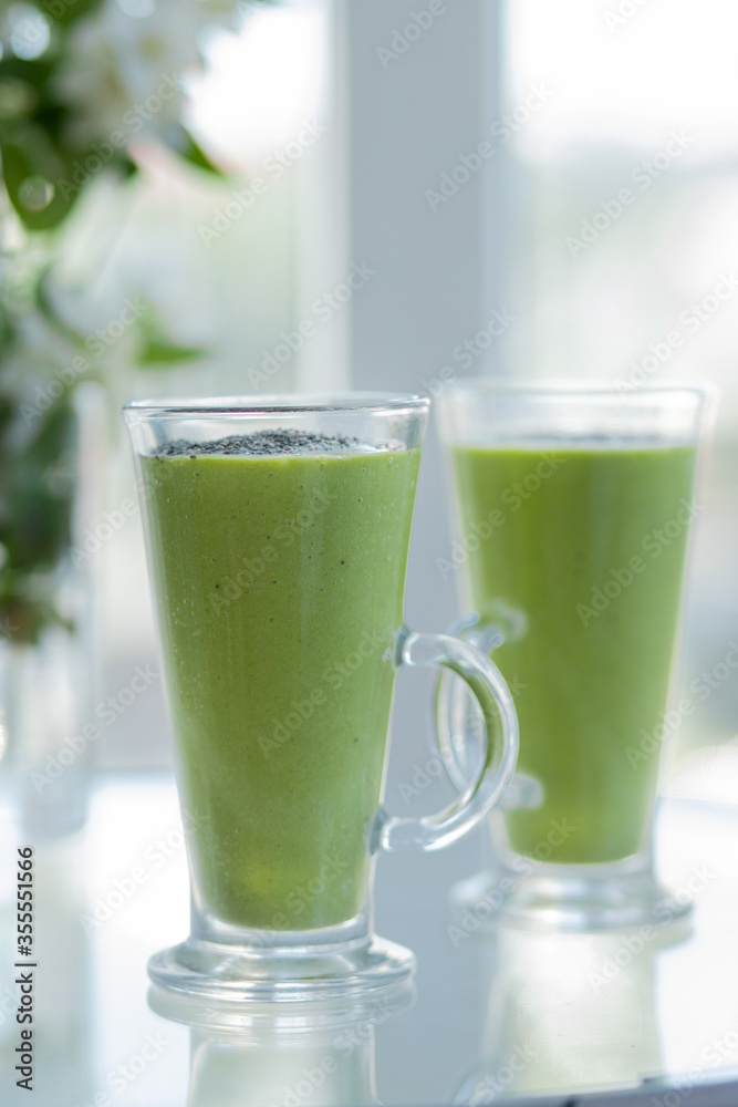 for breakfast two green cocktail detox smoothies on the glass table. Side view for breakfast two green cocktail detox smoothies on the glass table. Side view