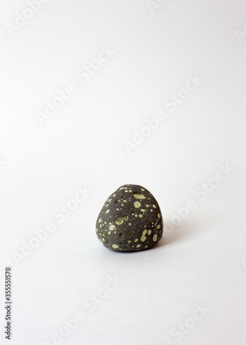 Gray stone in white spots on a white background. Smooth, sea stone. Pebbles.