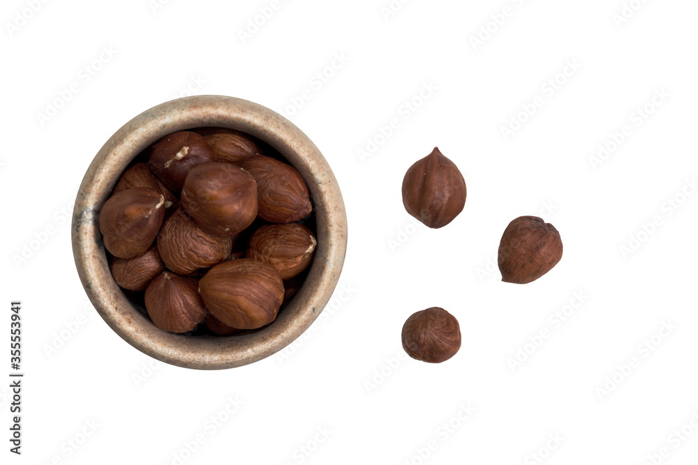 Hazelnuts in a bowl and three hazelnuts on the outside on a white background Hazelnuts in a bowl and three hazelnuts on the outside on a white background