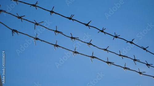 Rusty barbed wire against a cloudy sky. Serving a sentence behind barbed wire. Fencing.