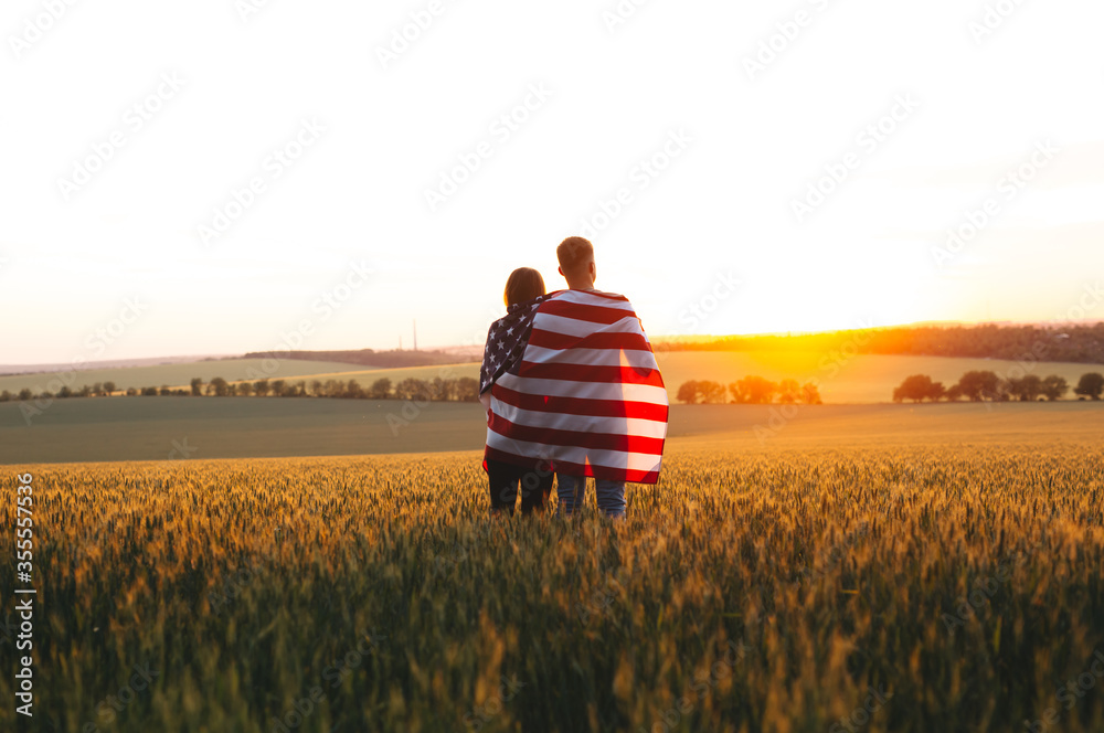 Φωτογραφία Image of young family with the American flag in a wheat field at sunset