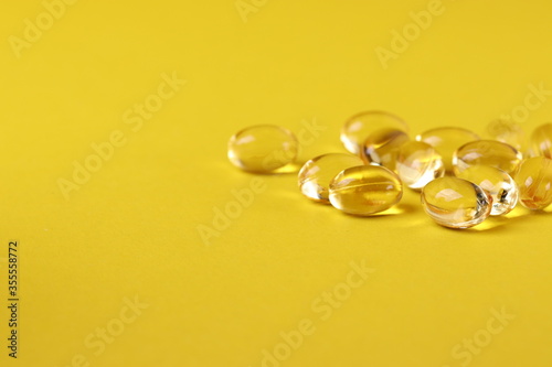  fish oil omega three capsules on the yellow background as a healthy balanced diet concept or vitamin supplement consumption