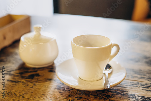Aromatic fresh coffee in a white cup. Americano with sugar bowl on table in cafe. Americano in a small white cup.