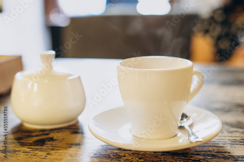 Aromatic fresh coffee in a white cup. Espresso in a small white cup and a sugar bowl in a summer cafe. Fragrant fresh coffee in a restaurant.
