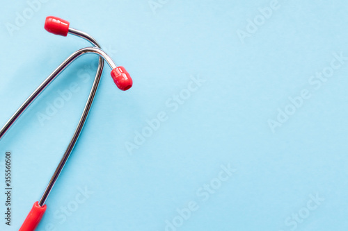 Medical equipment: red stethoscope on a light blue background with a place for text. Copy space. Medical concept.