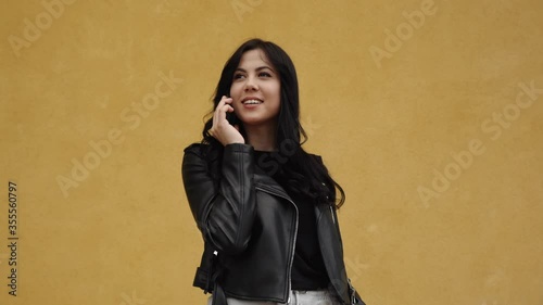 Brunette woman talking to the phone on the yellow