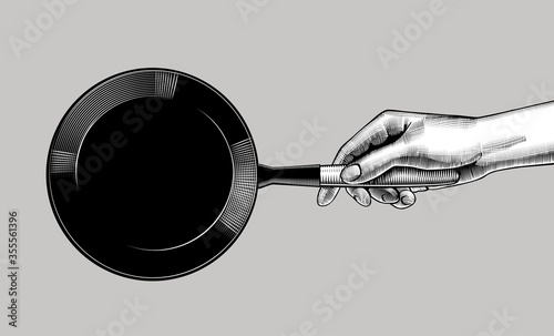 Engraved drawing of female hand with a black frying pan