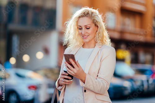Happy business woman using smartphone on the street