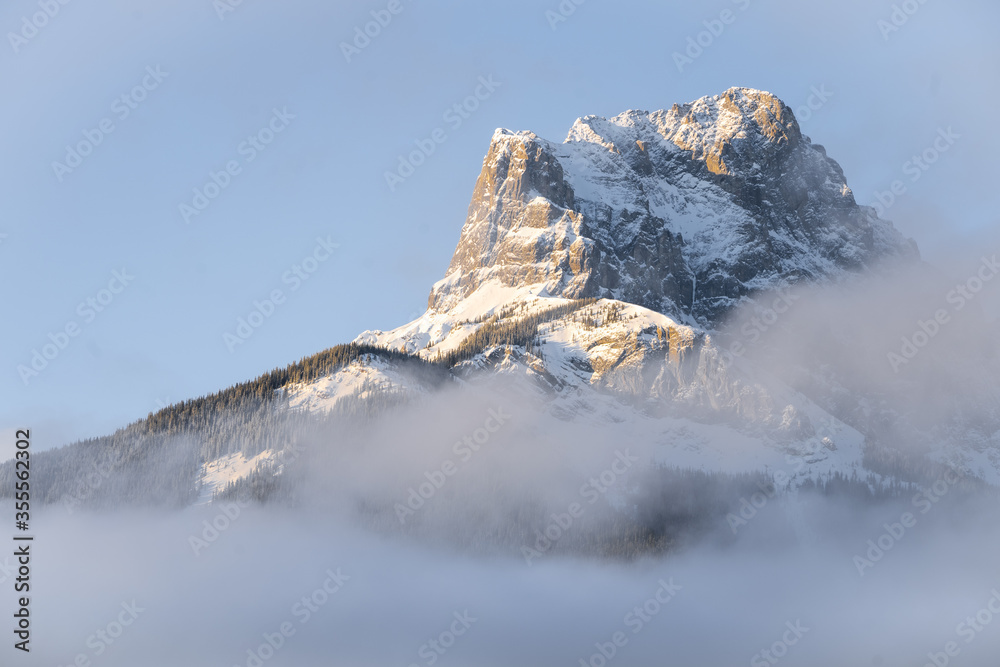 Mountain peak catching first sun rays during sunrise, shot at Three Sisters Mountain, Canmore, Alberta, Canada