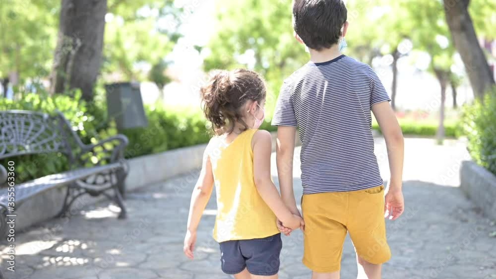 Happy childs running with the protection mask in the park. New normal, boys running with happiness after confinement Happy childs running with the protection mask in the park. New normal, boys running with happiness after confinement