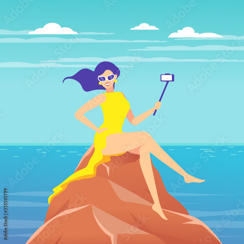 A woman takes a selfie, videotaping with the help of a selfie stick against the background of the sea landscape.