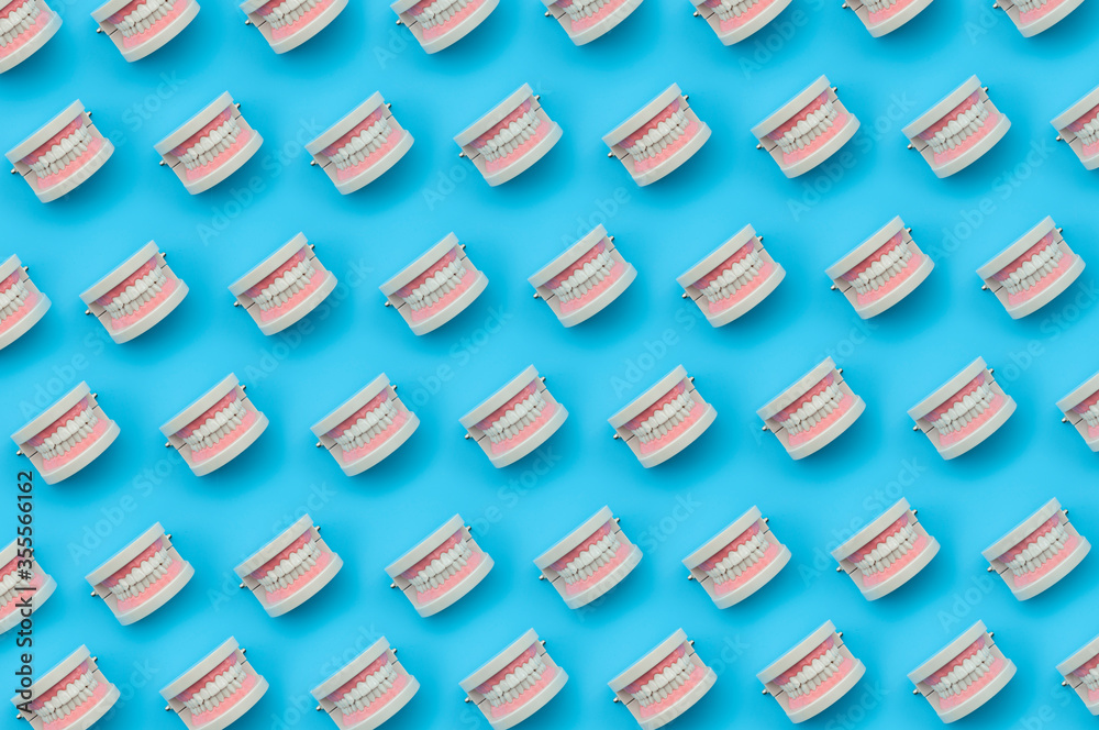 Dental hygiene treatment, tooth anatomy and dentist checkup concept with minimalist full frame seamless pattern of medical teeth model isolated on blue background Dental hygiene treatment, tooth anatomy and dentist checkup concept with minimalist full frame seamless pattern of medical teeth model isolated on blue background