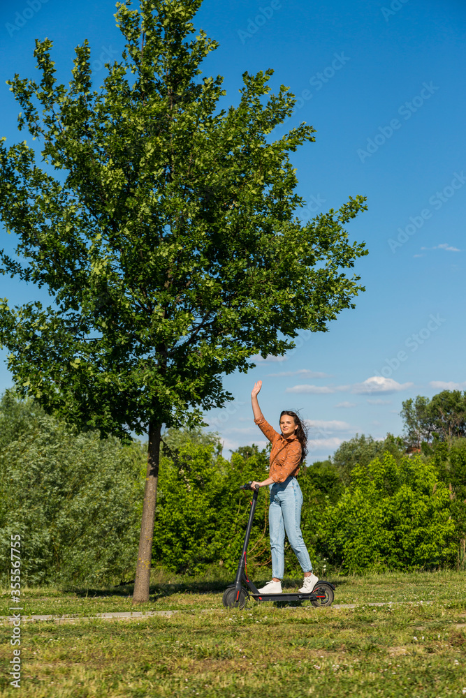 A young girl is driving an electric scooter and waving A young girl is driving an electric scooter and waving