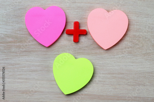 Three blank heart shaped stickers with plus sign. Creative symbolic background
