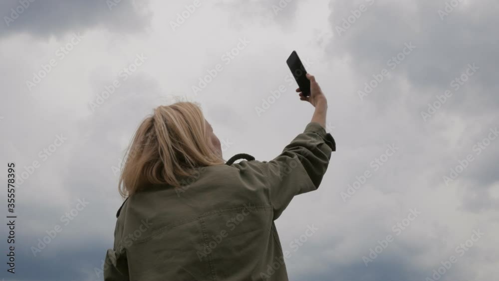 A woman tries to catch a mobile signal by holding up her smartphone