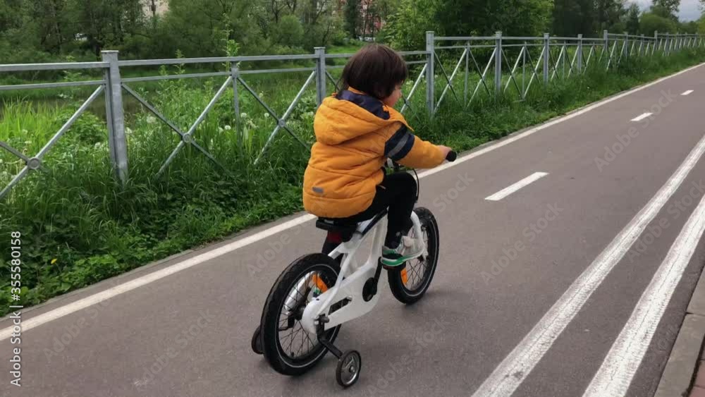 little boy rides a children's bike on a bike path little boy rides a children's bike on a bike path