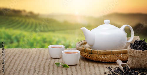Warm cup of tea with teapot, green tea leaves and dried herbs at morning in plantations with panorama background empty space for text, Organic product from the nature for healthy with traditional