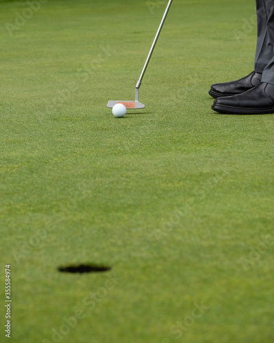 Man putting golf ball on green to hole, close up view