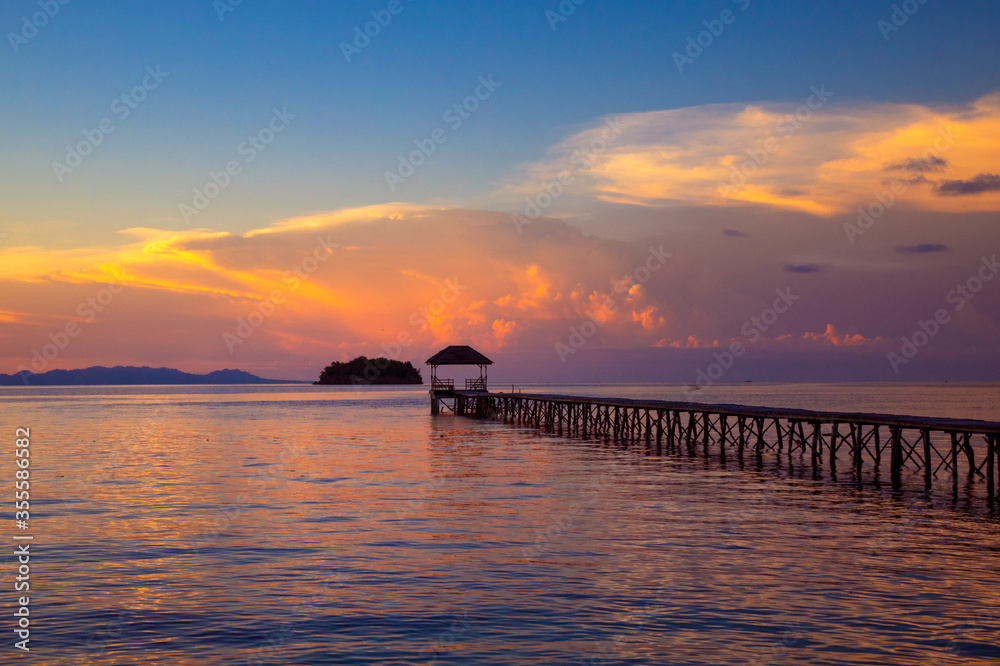Naklejka premium beach with walkway to the sea at sunset