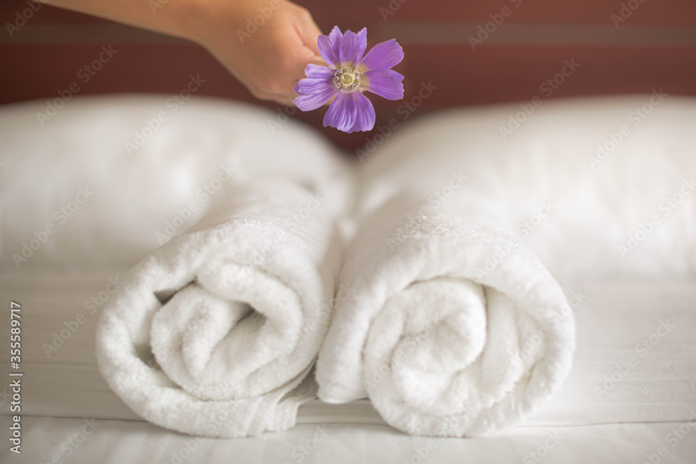 A close up of a maid placing a flower on a set of towels on the hotel bed A close up of a maid placing a flower on a set of towels on the hotel bed