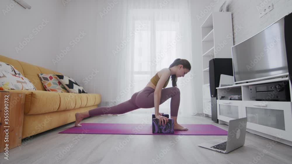 Young beautiful woman is practicing stretch legs on violet mat, she using two bricks to support Young beautiful woman is practicing stretch legs on violet mat, she using two bricks to support