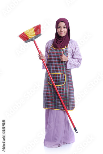 Muslim asian wife holding a broom