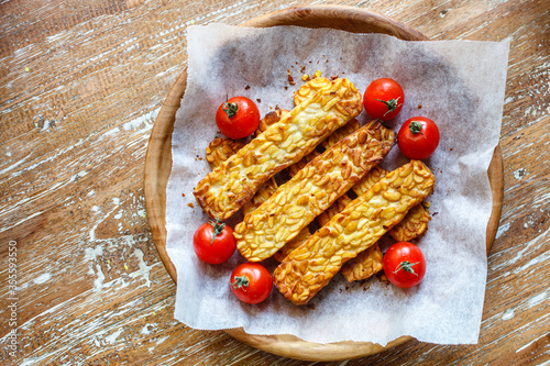 Bild auf Leinwand Fried tempeh or tempe (traditional Indonesian soy product) and cherry tomatoes on wooden surface