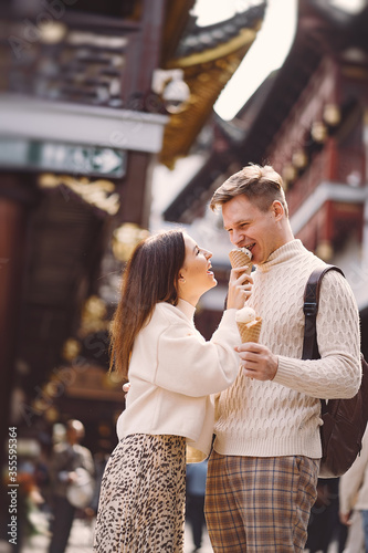 newlywed couple eating ice cream from a cone on a street in Shanghai near Yuyuan. Couple take a break for a snack while visiting China. husband and wife sharing ice cream outisde of a food hall