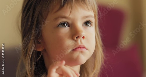 Adorable little girl in the sunlit living room watching tv and eating cereals