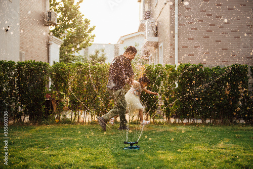 A pair of Asian father and daughter playing with water in the yard