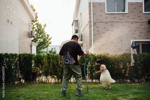 A pair of Asian father and daughter playing with water in the yard