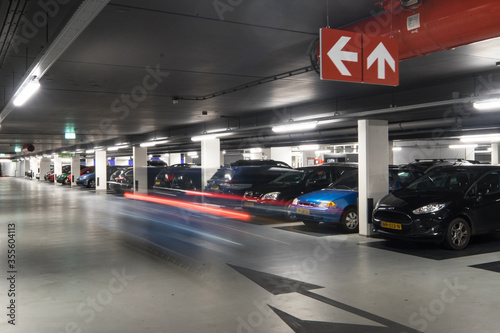 Underground parking garage with parked cars and stripes of light from a car passing by