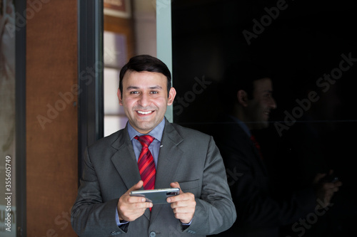 Smiling businessman with smart phone outdoors on the street, with copy space.New lower prices High-quality images for all your projects ₹345 for this image ₹170 with a 1-month subscription 10 images