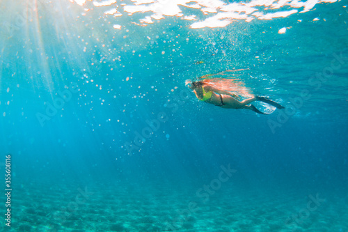 Young woman doing snorkelling in the crystal water of the Mediterranean Sea
