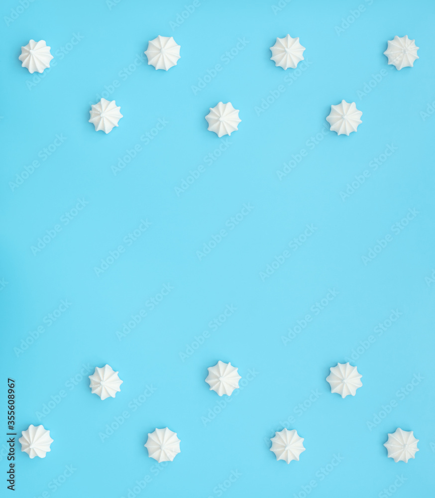 Delicious white merengues on blue background. Happy day, breakfast, good morning concepts. Time for tea or coffee. Greeting or invitation card. Flat lay style with copy space.