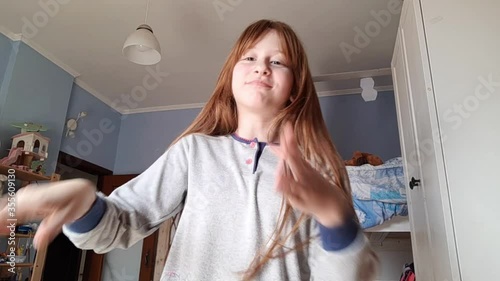 Little redhead girl enjoying dancing in front of smartphone camera making video for a social network.