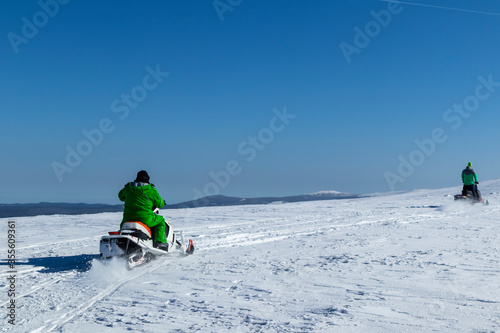 Rider on the snowmobile in the mountains ski resort. A man is riding snowmobile in mountains