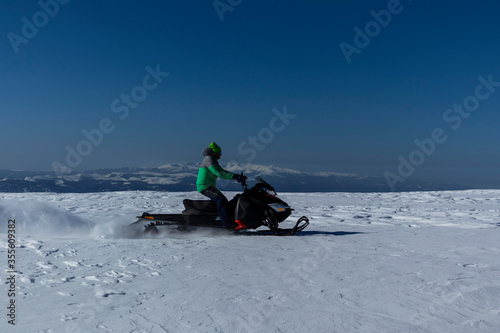 Rider on the snowmobile in the mountains ski resort. A man is riding snowmobile in mountains © Gabriel Teleptean