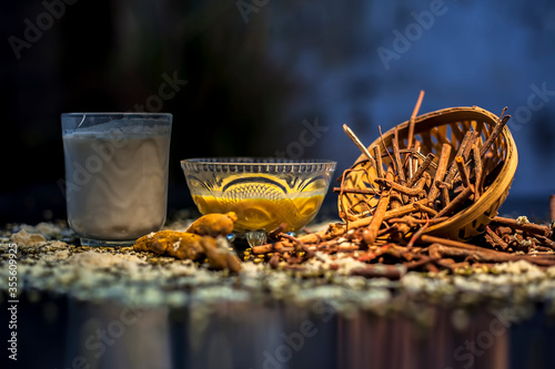 Ayurvedic blood purifier and skin glow face mask consisting of Manjistha, mung bean, haldi/turmeric, and milk. Horizontal shot of face mask with entire constituents with it on a black surface. photo