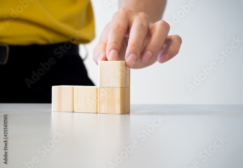 conceptual businessman fingers arranging  wooden blocks